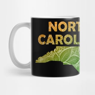 Colorful mandala art map of North Carolina with text in green and orange Mug